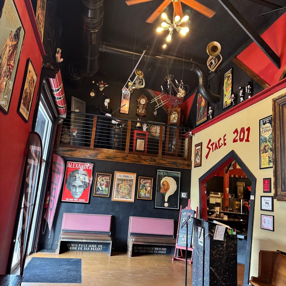 Vibrant, two-level restaurant interior featuring theatrical posters, musical instruments, and unique decor.