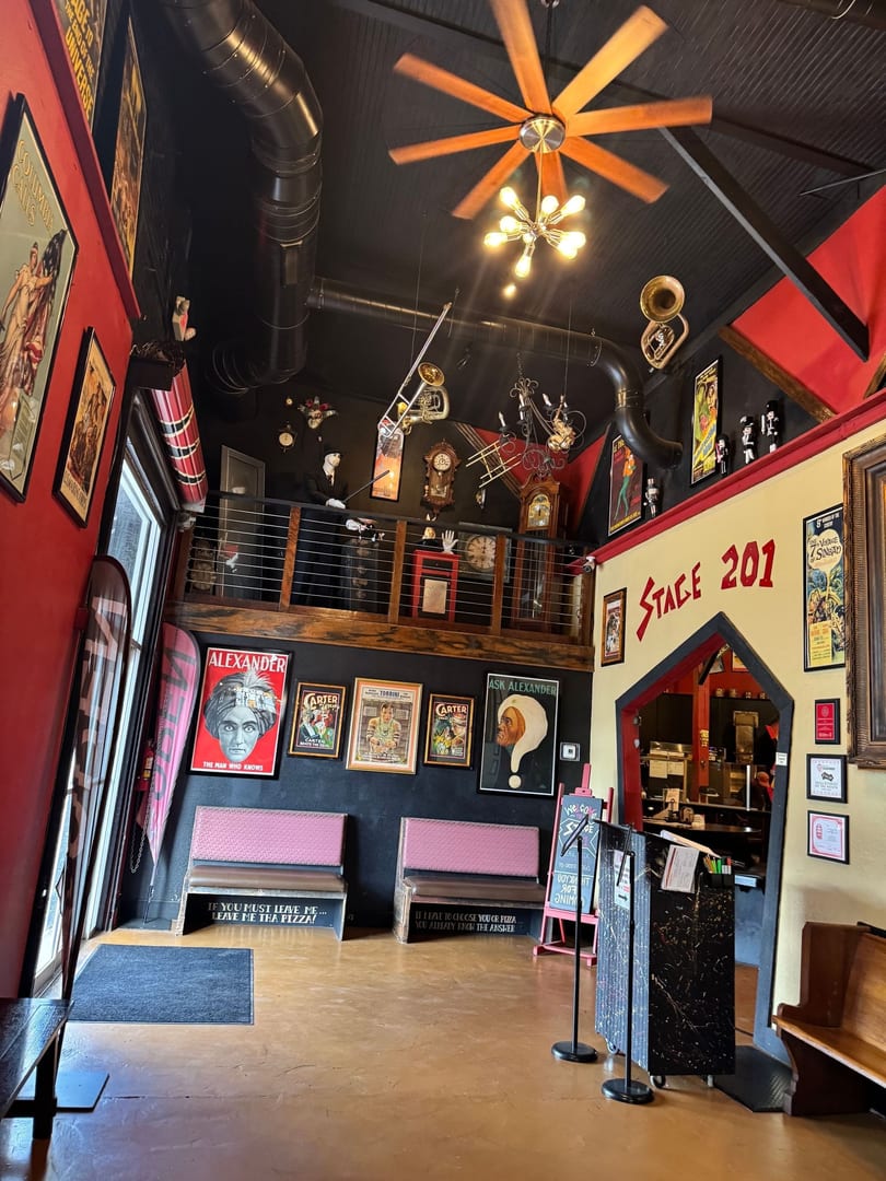 Vibrant, two-level restaurant interior featuring theatrical posters, musical instruments, and unique decor.